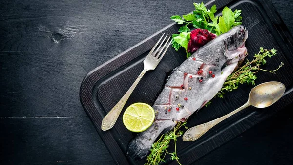 Balık alabalık aromatik otlar ve baharatlar ile. Ahşap arka plan üzerinde.