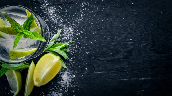 Limon ve nane kokteyli, buz, siyah ahşap yüzeye. Üstten Görünüm. Boş alan.