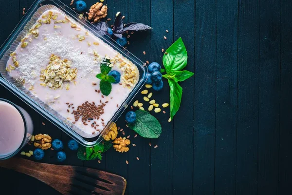 Yaban mersini ve yoğurt ile yulaf ezmesi gevreği. Sağlıklı bir diyet yemek. Öğle Yemeği boks. Siyah ahşap arka plan üzerinde. Üstten Görünüm. Metin için boş alan.