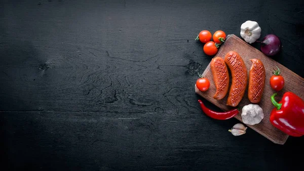 Taze sebze ile bir tavada ızgara sosis. Siyah yüzeyi ahşap. Üstten Görünüm.