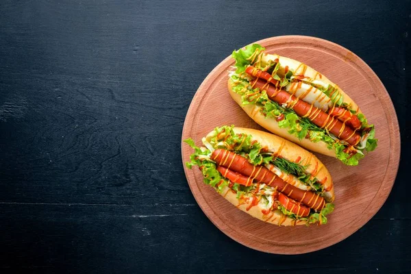 Hot Dog mit Grillwurst, Senf und Ketchup, Zwiebeln und Gemüse auf Holzuntergrund. Ansicht von oben. Freiraum. — Stockfoto