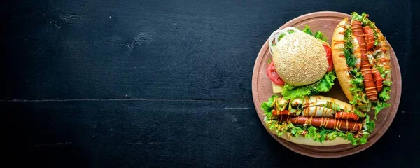 Sosisli sandviç ve hamburger ile peynir, et ve Yeşiller ahşap arka plan üzerinde. Üstten Görünüm. Boş alan.