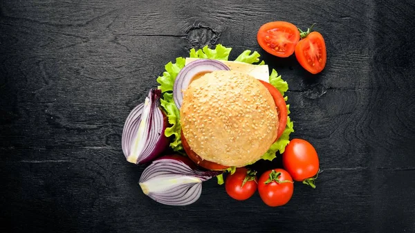 Peynir, et, domates ve soğan ve otlar ile hamburger. Ahşap arka plan üzerinde. Üstten Görünüm. Boş alan.