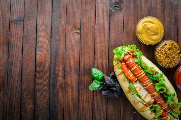 Hot dog con hierbas y especias, mostaza y ketchup. Sobre fondo de madera. Espacio de visualización superior . — Foto de Stock