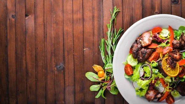 Salata taze salatalık, domates ve yeşillik bir plaka ahşap tahta üzerinde ızgara et ile. Üstten Görünüm. Boş alan.