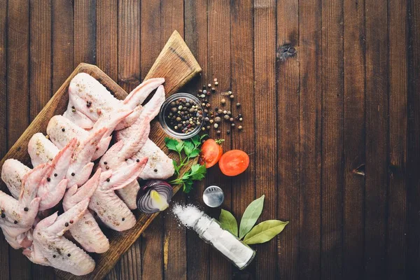 Baharat ile çiğ tavuk kanatları. Ahşap yüzeyde. Üstten Görünüm.