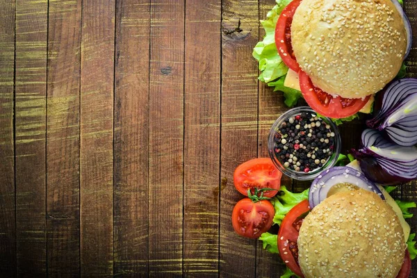 Peynir, et, domates ve soğan ve otlar ile hamburger. Ahşap arka plan üzerinde. Üstten Görünüm. Boş alan.