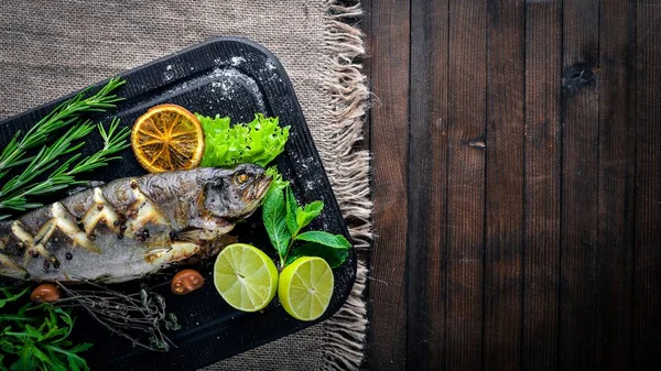 Alabalık balık pişmiş aromatik otlar ve baharatlar ile. Ahşap arka plan üzerinde.