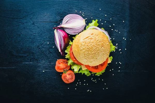 Peynir, et, domates ve soğan ve otlar ile hamburger. Ahşap arka plan üzerinde. Üstten Görünüm. Boş alan.