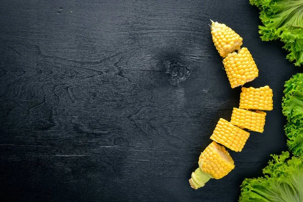 Du maïs. Légumes crus Sur un fond en bois noir. Vue de dessus. Espace libre pour votre texte . — Photo