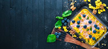 Yaban mersini ve yoğurt ile yulaf ezmesi gevreği. Sağlıklı diyet yiyecek. Öğle Yemeği boks. Siyah ahşap arka plan üzerinde. Üstten Görünüm. Metin için boş alan.