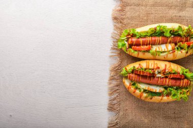 Sosis ızgara sosis, hardal ve ketçap, soğan ve Yeşiller ahşap arka plan üzerinde. Üstten Görünüm. Boş alan.