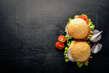 Peynir, et, domates ve soğan ve otlar ile hamburger. Ahşap arka plan üzerinde. Üstten Görünüm. Boş alan.