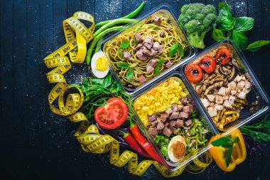 Makarna ve buğday eti ve taze sebze ile. Sağlıklı bir diyet yemek. Öğle Yemeği boks. Siyah ahşap arka plan üzerinde. Üstten Görünüm. Metin için boş alan.