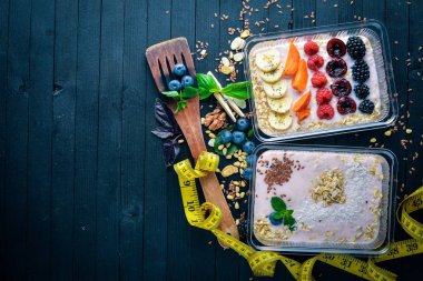 Yoğurt ve meyve ile yulaf gevreği. Sağlıklı bir diyet yemek. Öğle Yemeği boks. Siyah ahşap arka plan üzerinde. Üstten Görünüm. Metin için boş alan.