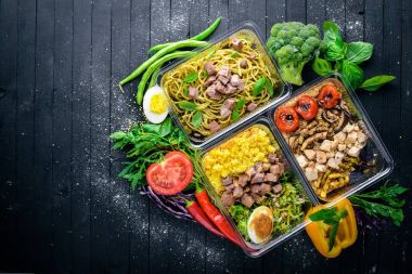 Makarna ve buğday eti ve taze sebze ile. Sağlıklı bir diyet yemek. Öğle Yemeği boks. Siyah ahşap arka plan üzerinde. Üstten Görünüm. Metin için boş alan.