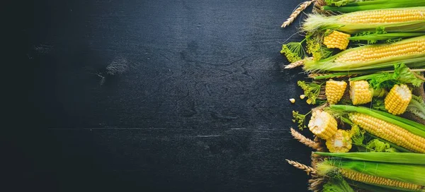 Mısır. Çiğ sebze siyah bir ahşap zemin üzerine. Üstten Görünüm. Metniniz için boş alan.