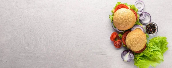 Hambúrguer com queijo, carne, tomate e cebola e ervas. Sobre fundo de madeira. Vista superior. Espaço livre . — Fotografia de Stock