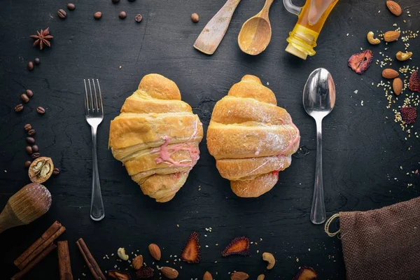 Croissant with yogurt. Pastry dough. On a black wooden background. Free space for text . Top view,
