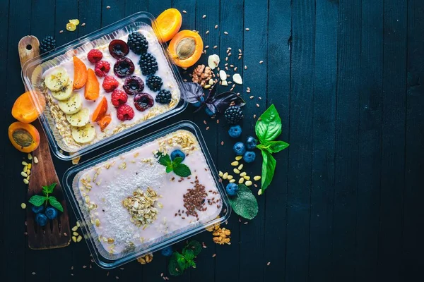 Haferflocken mit Joghurt und Früchten. gesunde Ernährung. Lunchboxen. auf schwarzem Holzgrund. Ansicht von oben. Freiraum für Text. — Stockfoto