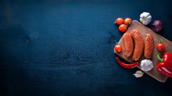 Taze sebze ile bir tavada ızgara sosis. Siyah yüzeyi ahşap. Üstten Görünüm.