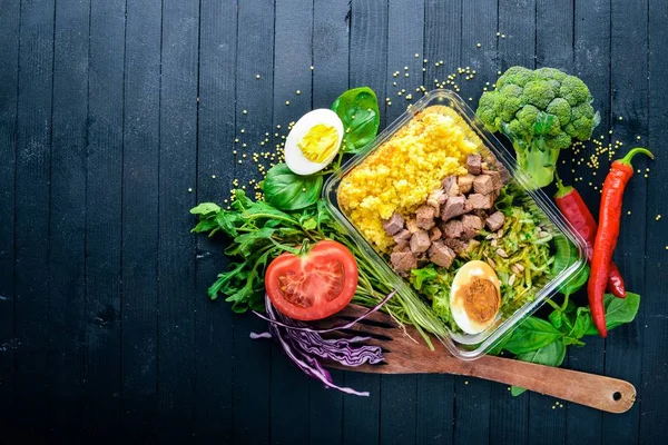 Poached porridge with meat and fresh vegetables. Healthy Diet Food. Lunch Boxing. On a black wooden background. Top view. Free space for text. — Stock Photo, Image