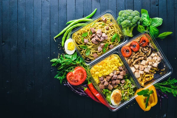 Nudeln und Buchweizen mit Fleisch und frischem Gemüse. gesunde Ernährung. Lunchboxen. auf schwarzem Holzgrund. Ansicht von oben. Freiraum für Text. — Stockfoto