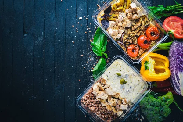 Makarna ve buğday eti ve taze sebze ile. Sağlıklı bir diyet yemek. Öğle Yemeği boks. Siyah ahşap arka plan üzerinde. Üstten Görünüm. Metin için boş alan.