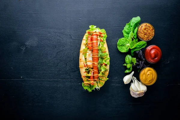 Sosis ızgara sosis, hardal ve ketçap, soğan ve Yeşiller ahşap arka plan üzerinde. Üstten Görünüm. Boş alan.