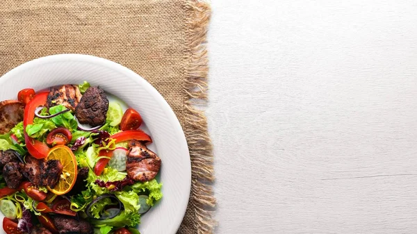 Salata taze salatalık, domates ve yeşillik bir plaka ahşap tahta üzerinde ızgara et ile. Üstten Görünüm. Boş alan.