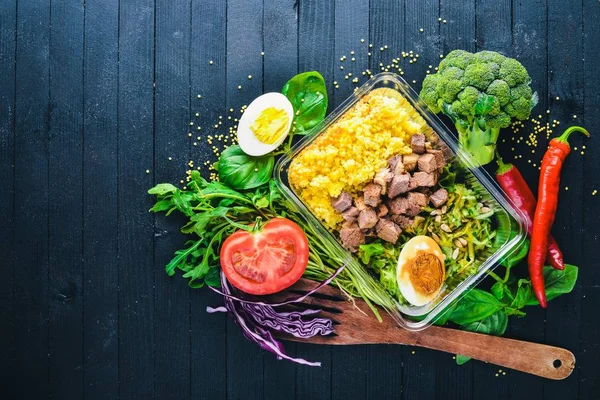 Poached porridge with meat and fresh vegetables. Healthy Diet Food. Lunch Boxing. On a black wooden background. Top view. Free space for text. — Stock Photo, Image