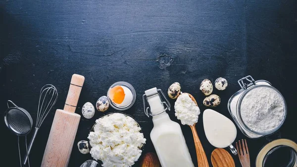 Süt ve süt ürünleri. Peynir, peynir, süt, ekşi krema, siyah ahşap zemin. Üstten Görünüm. Boş alan.