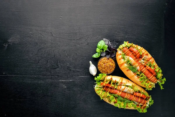 Sosis ızgara sosis, hardal ve ketçap, soğan ve Yeşiller ahşap arka plan üzerinde. Üstten Görünüm. Boş alan.