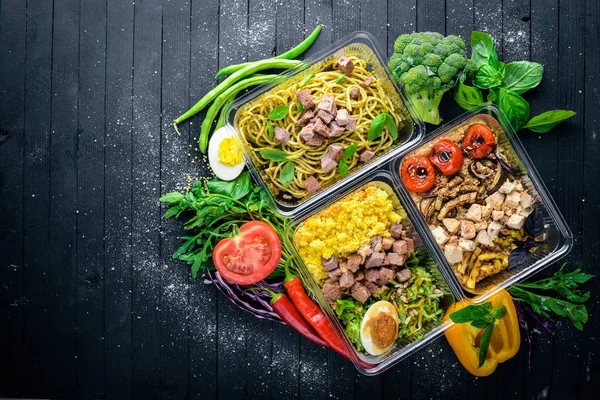 Makarna ve buğday eti ve taze sebze ile. Sağlıklı bir diyet yemek. Öğle Yemeği boks. Siyah ahşap arka plan üzerinde. Üstten Görünüm. Metin için boş alan.