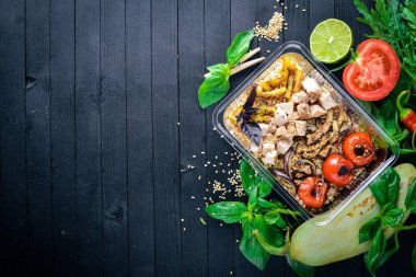 Risotto pirinci et ve ızgara sebzeler ile. Sağlıklı bir diyet yemek. Öğle Yemeği boks. Siyah ahşap arka plan üzerinde. Üstten Görünüm. Metin için boş alan.