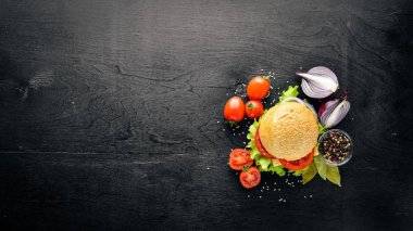 Peynir, et, domates ve soğan ve otlar ile hamburger. Ahşap arka plan üzerinde. Üstten Görünüm. Boş alan.