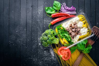 Et ve taze sebze ile makarna. Sağlıklı bir diyet yemek. Öğle Yemeği boks. Siyah ahşap arka plan üzerinde. Üstten Görünüm. Metin için boş alan.