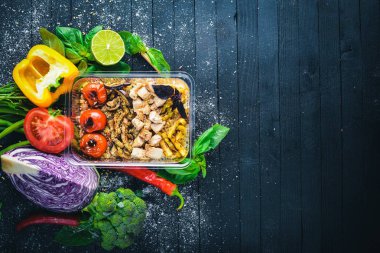 Risotto pirinci et ve ızgara sebzeler ile. Sağlıklı bir diyet yemek. Öğle Yemeği boks. Siyah ahşap arka plan üzerinde. Üstten Görünüm. Metin için boş alan.