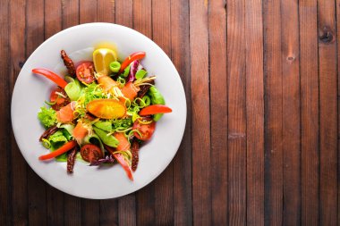 Salata somon ve taze sebze ve otlar. İtalyan mutfağı. Üstten Görünüm. Ahşap arka plan üzerinde.