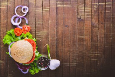 Peynir, et, domates ve soğan ve otlar ile hamburger. Ahşap arka plan üzerinde. Üstten Görünüm. Boş alan.