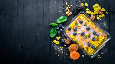 Yaban mersini ve yoğurt ile yulaf ezmesi gevreği. Sağlıklı diyet yiyecek. Öğle Yemeği boks. Siyah ahşap arka plan üzerinde. Üstten Görünüm. Metin için boş alan.