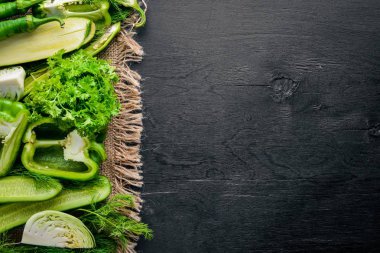 Yeşil sebzeler büyük bir set keten kumaş, ahşap zemin üzerinde ortaya koydu. Üstten Görünüm. Boş alan.