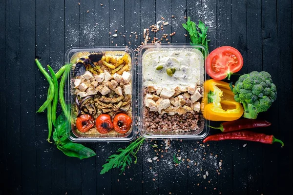 Makarna ve buğday eti ve taze sebze ile. Sağlıklı bir diyet yemek. Öğle Yemeği boks. Siyah ahşap arka plan üzerinde. Üstten Görünüm. Metin için boş alan.