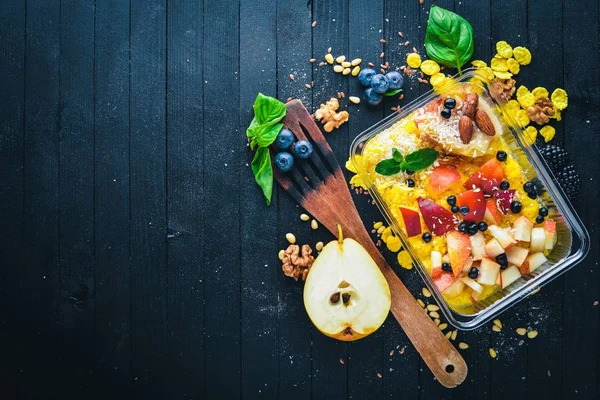 Taze meyve ve yoğurt yulaf ezmesi. Sağlıklı bir diyet yemek. Öğle Yemeği boks. Siyah ahşap arka plan üzerinde. Üstten Görünüm. Metin için boş alan.