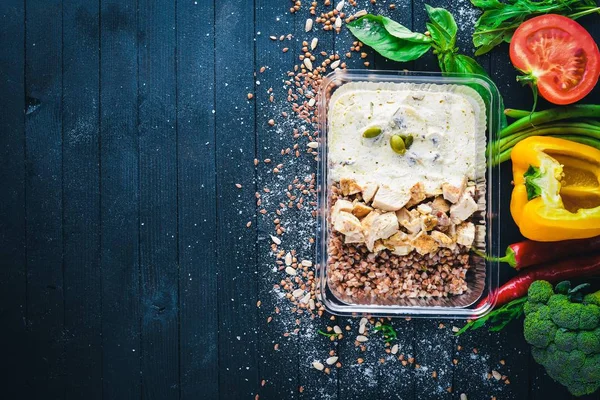 Buğday eti ve taze sebze ile. Sağlıklı bir diyet yemek. Öğle Yemeği boks. Siyah ahşap arka plan üzerinde. Üstten Görünüm. Metin için boş alan.