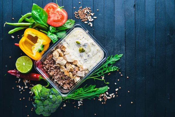 Buğday eti ve taze sebze ile. Sağlıklı bir diyet yemek. Öğle Yemeği boks. Siyah ahşap arka plan üzerinde. Üstten Görünüm. Metin için boş alan.