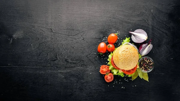 Peynir, et, domates ve soğan ve otlar ile hamburger. Ahşap arka plan üzerinde. Üstten Görünüm. Boş alan.