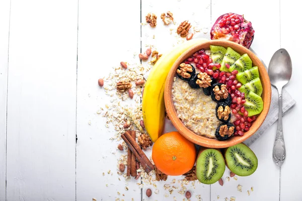 Healthy food: porridge with fruit kiwi, banana and nuts. On Wooden background. Top view. — Stock Photo, Image
