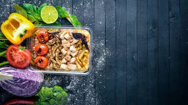 Risotto pirinci et ve ızgara sebzeler ile. Sağlıklı bir diyet yemek. Öğle Yemeği boks. Siyah ahşap arka plan üzerinde. Üstten Görünüm. Metin için boş alan.