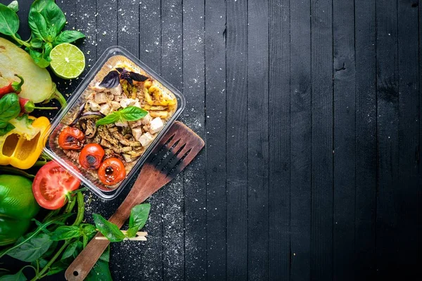 Risotto pirinci et ve ızgara sebzeler ile. Sağlıklı bir diyet yemek. Öğle Yemeği boks. Siyah ahşap arka plan üzerinde. Üstten Görünüm. Metin için boş alan.